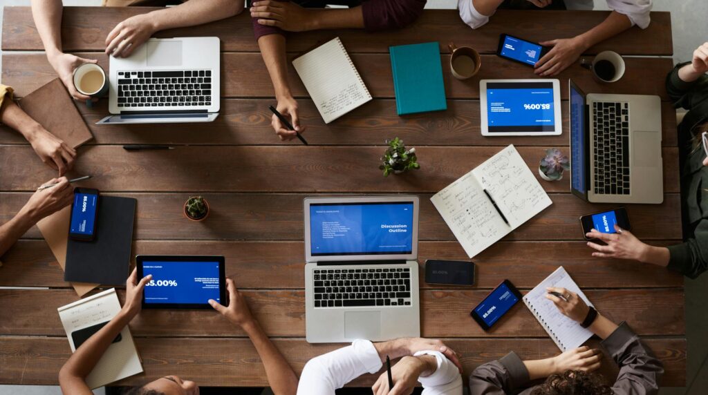 Overhead view of a diverse team in a business meeting using laptops and tablets.